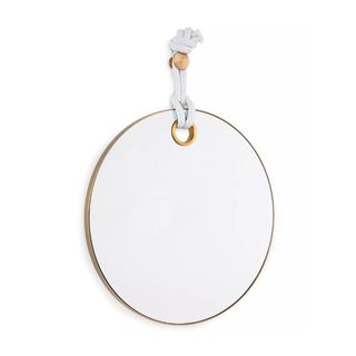 A round mirror with a gold border and a white rope hanger