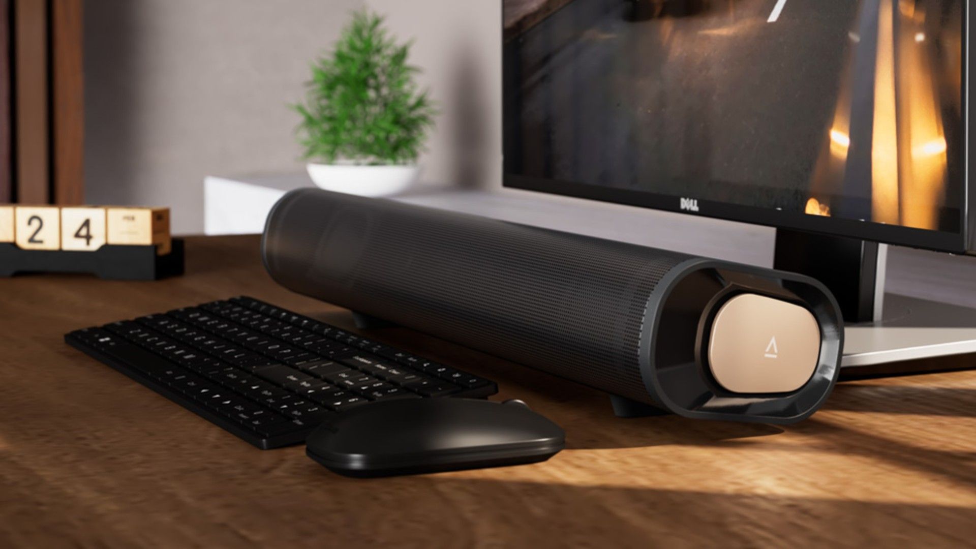 A Creative Stage Pro soundbar between a computer keyboard and monitor on a wooden desk