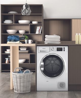 A Hotpoint washing machine appliance in kitchen with wooden shelving decor