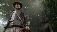 Screenshot from Indiana Jones and the Great Circle showing Indy from a top down position holding his whip in front of a statue and some trees