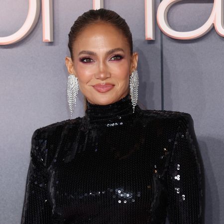 jennifer lopez attends a film premiere wearing a black gown and poses in front of a gray background