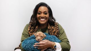 Alison Hammond in a green top holds puppy Oscar who is wrapped in a blanket in For the Love of Dogs with Alison Hammond