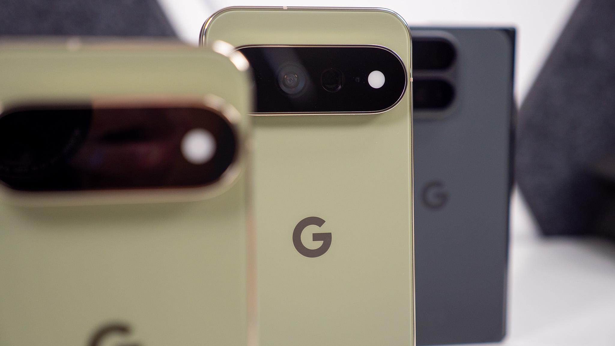 A Google Pixel 11 Pro XL in focus, with a Google Pixel 11 and Pixel 11 Pro Fold alongside