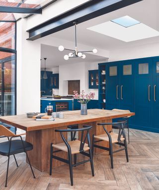 A large L-shaped kitchen extension with a separate dining area in front of blue floor to ceiling cabinets