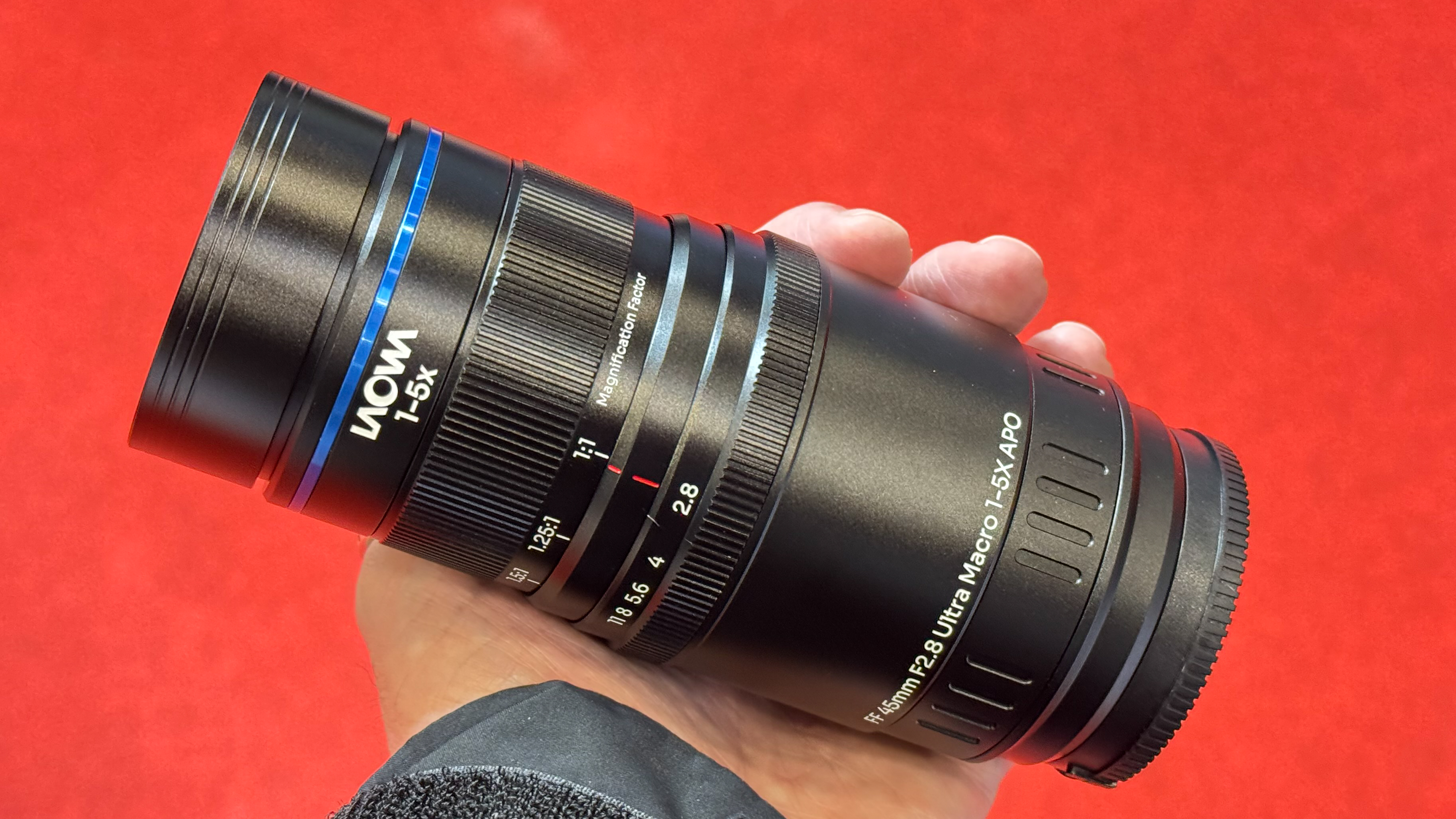 Laowa FF 45mm f/2.8 Ultra Macro 1-5x APO lens being held in man's hand