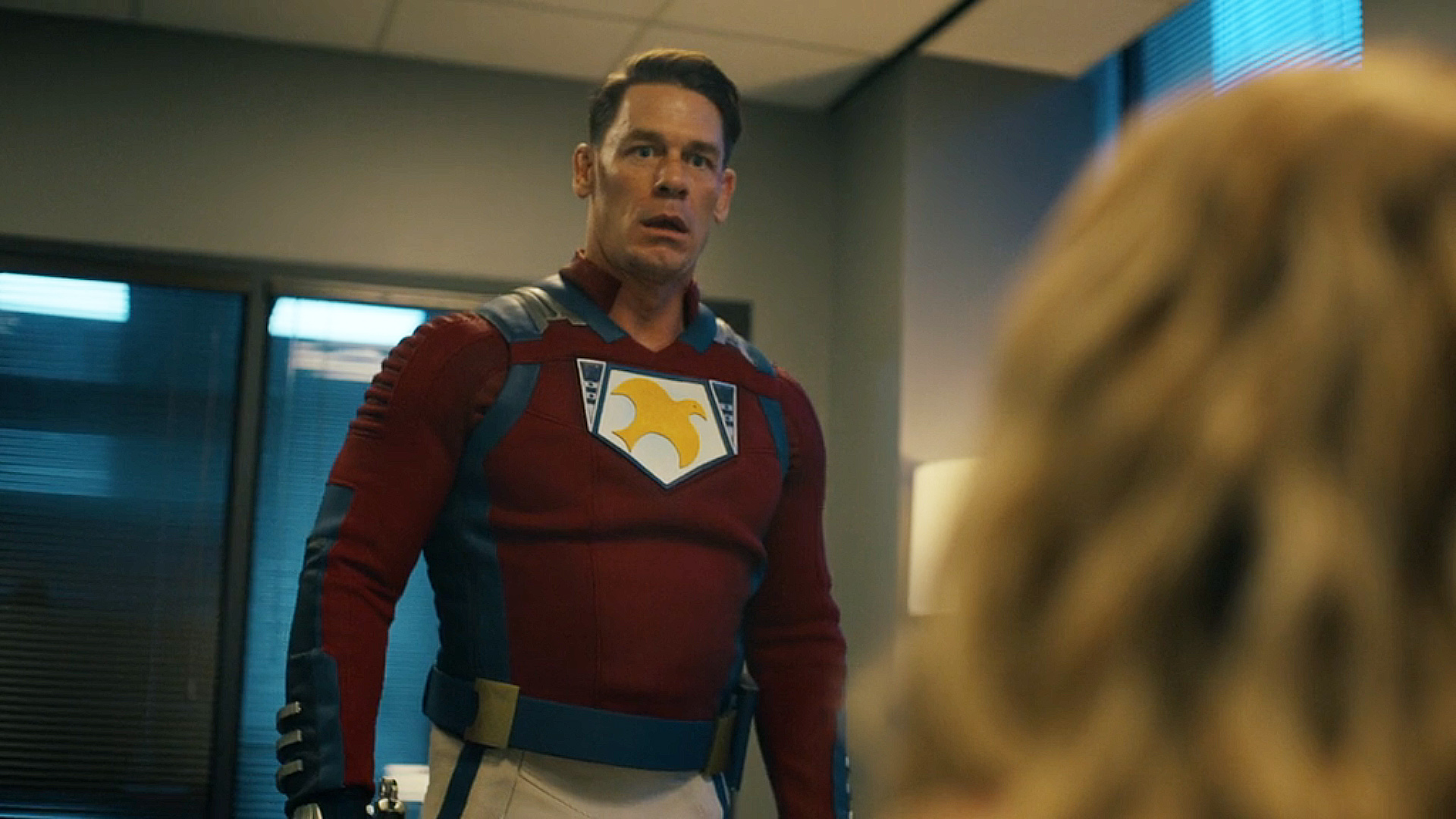 Chris Smith looking shocked at an off-camera Emilia Harcourt in Peacemaker season 2 episode 6