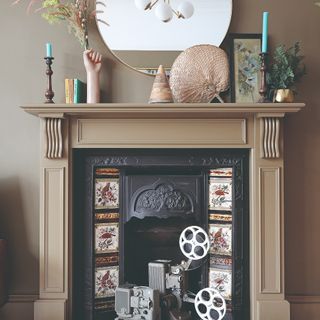 A beige-painted fireplace matching with the wall with a decorated mantelpiece and a round mirror hanging above it