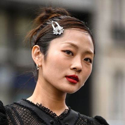a guest at a fashion show wears red lipstick, hair worn up with a silver flower slide - best kerastase products
