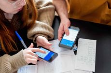 Two people pointing at their smartphones, calculating