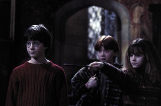 harry ron and hermiony look surprised in a dark room in Harry Potter and the Sorcerer’s Stone