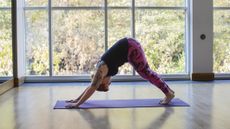Woman performing downward dog pose in a fitness studio