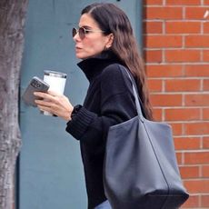 Sandra Bullock steps out in her signature understated style, wearing black knit turtleneck sweater paired with cuffed straight-leg jeans and sleek black Chelsea boots. 