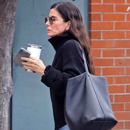 Sandra Bullock steps out in her signature understated style, wearing black knit turtleneck sweater paired with cuffed straight-leg jeans and sleek black Chelsea boots.