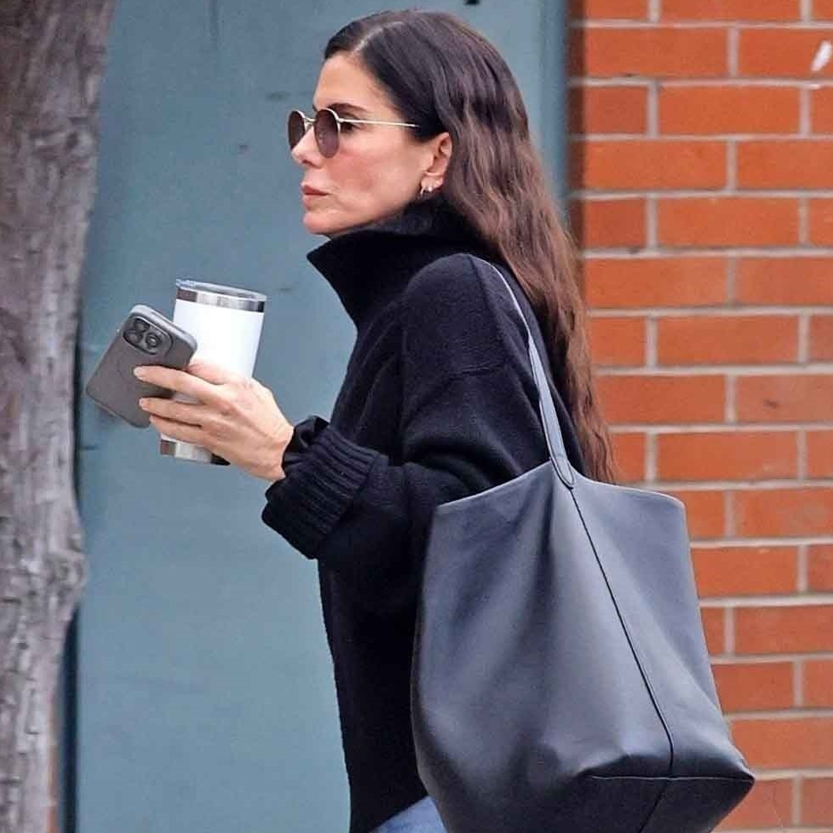 Sandra Bullock steps out in her signature understated style, wearing black knit turtleneck sweater paired with cuffed straight-leg jeans and sleek black Chelsea boots. 