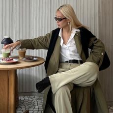 A woman sitting in a cafe in an autumnal outfit with creamy blonde hair