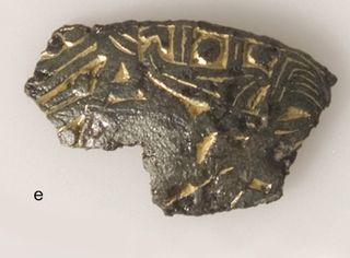 A fragment of a small brooch decorated in gilded relief.