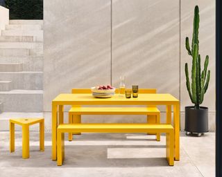A bright yellow aluminium outdoor picnic table and bench seats