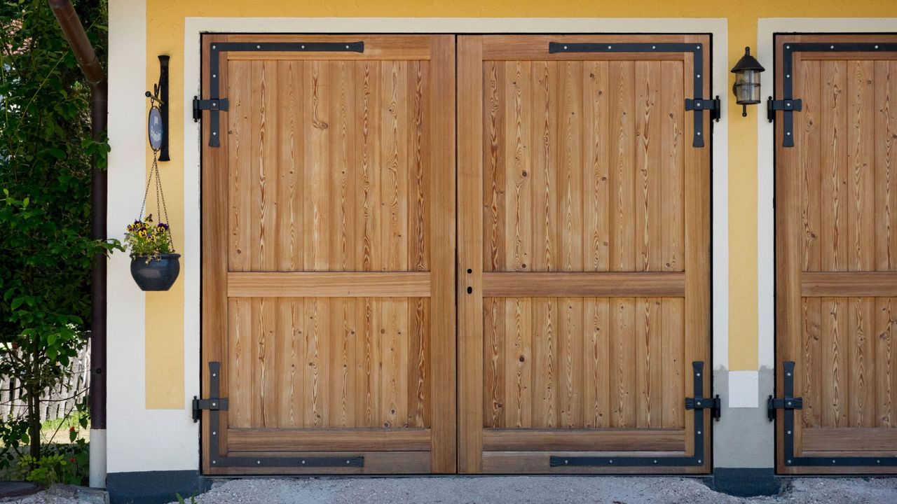 Finding out how to get rid of mice from a garage is useful. Here is a garage with wooden doors, framed with yellow and white walls with black wall sconces and a hanging basket 