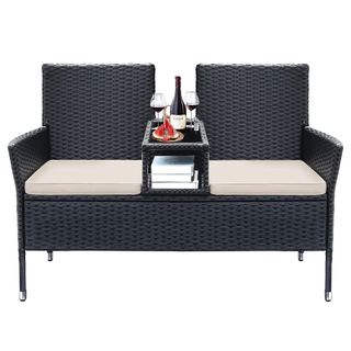 Rattan woven loveseat with white cushions and table in the middle