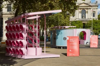 A pink and light blue-shaded outdoor installation comprises a light panel made of multiple spherical structures and a modernism-inspired, hollow home featuring an inner courtyard.