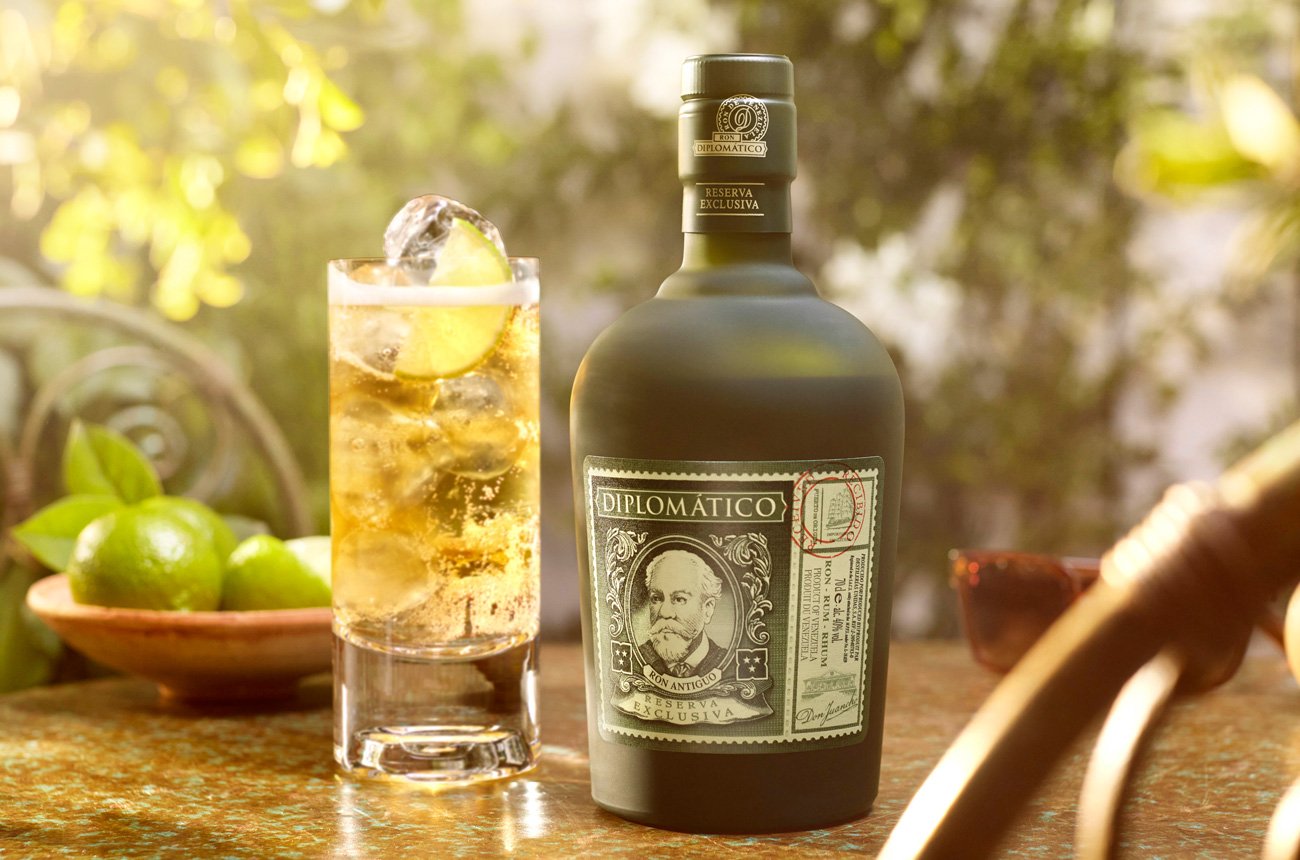 Bottle of rum, bowl of limes and cocktail on a table