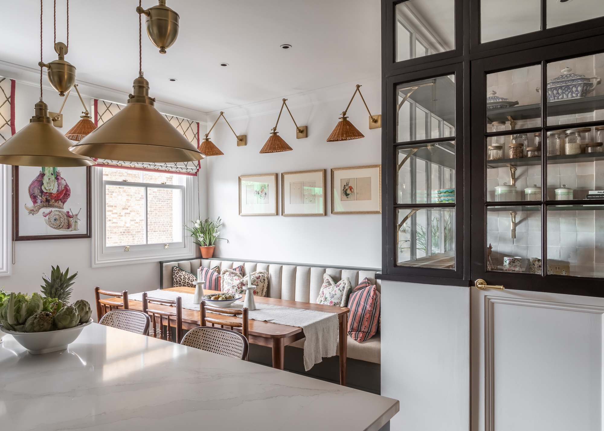 white kitchen with rattan wall lights, banquette seating and zellige tiles