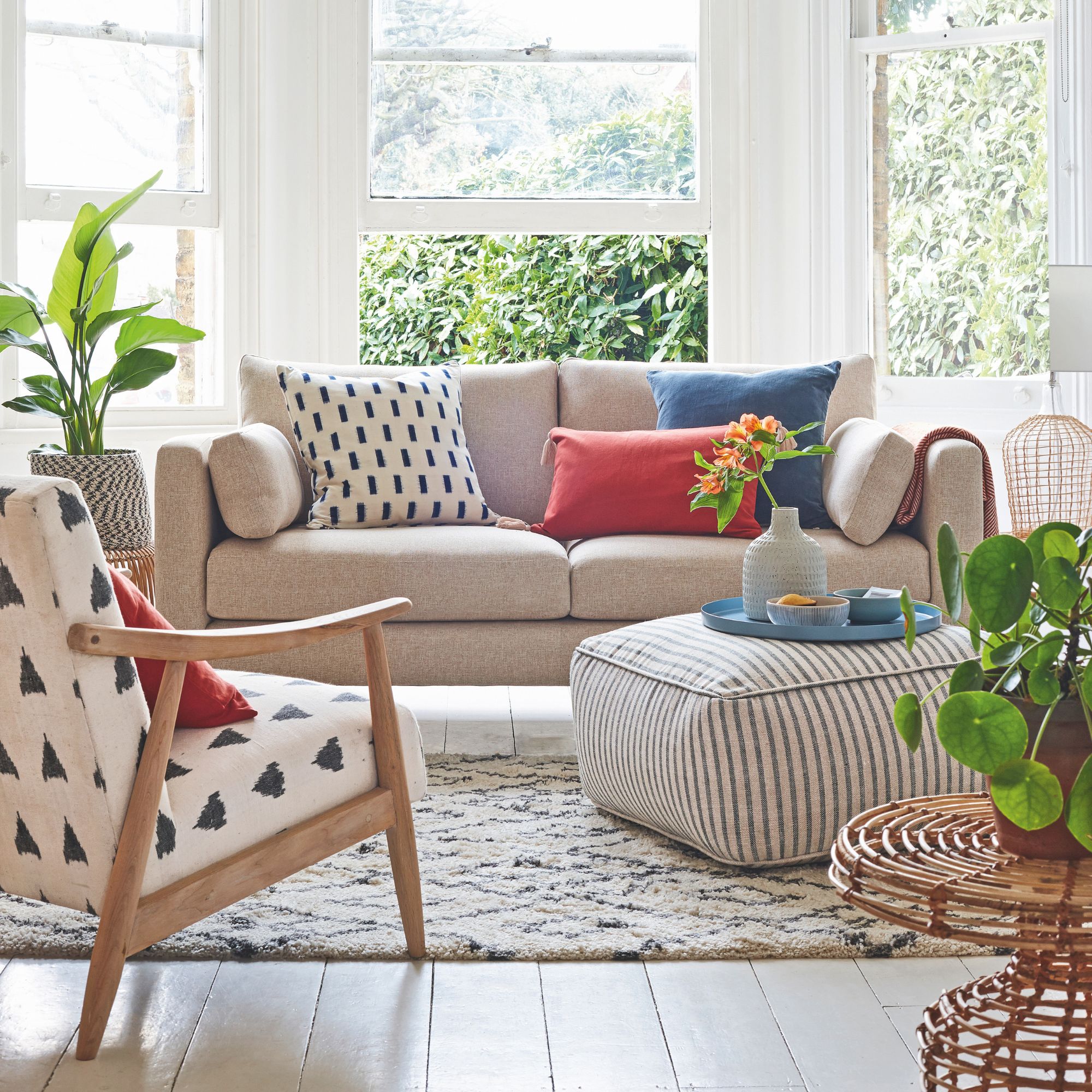 Living room with wooden floors and a rug on top, and a cream sofa and accent chair