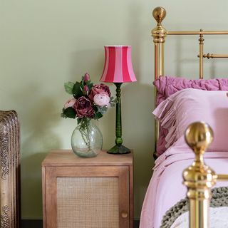 green bedroom with brass bed and bedside table