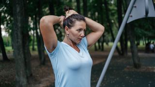 Woman tying up hair about to do running meditation in a woodland