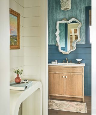 Cloakroom with blue shiplap paneling, blue wallpaper, wood vanity unit and a statement mirror