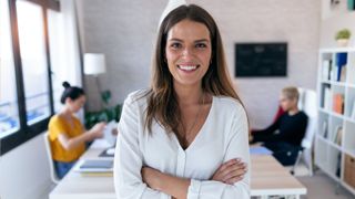 Female business owner smiling with arms crossed in her office