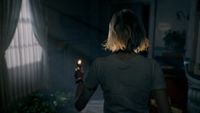 A character from Resident Evil walking in a room while holding a lighter.