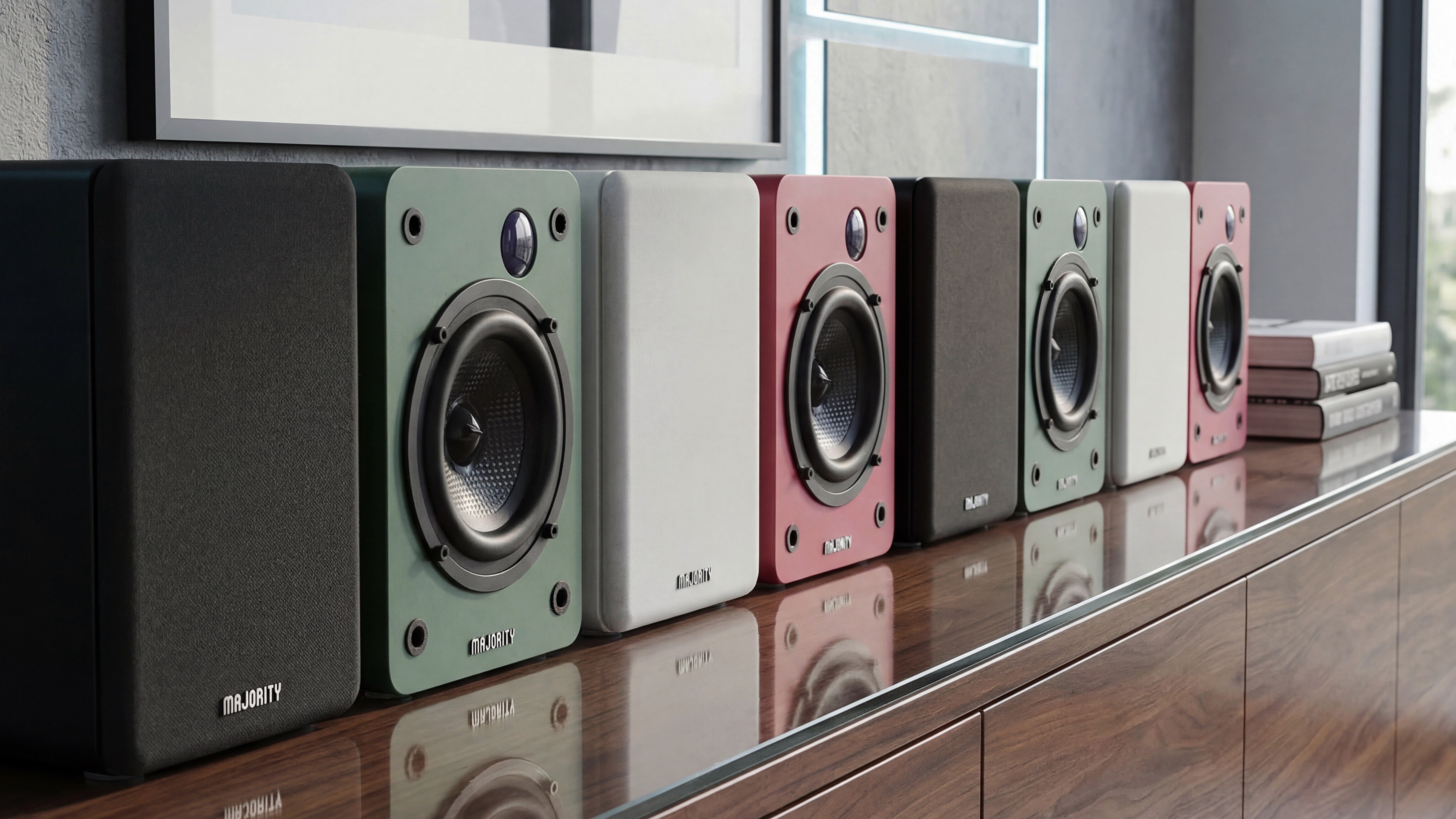 A row of different coloured Majority D50X speakers on a wooden side unit.