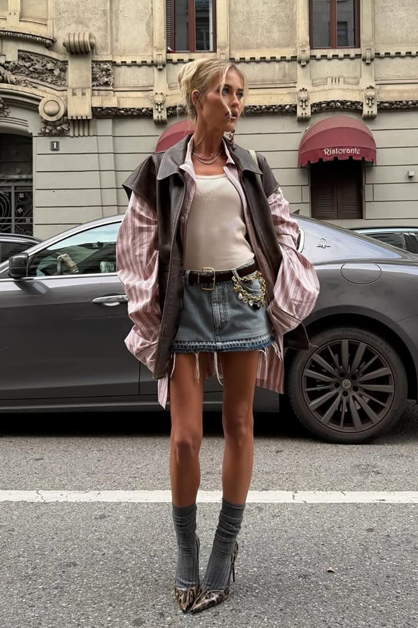 a woman wearing a brown button-down, blue denim skirt, striped burgundy button-down, gray socks, and pointed-toe shoes