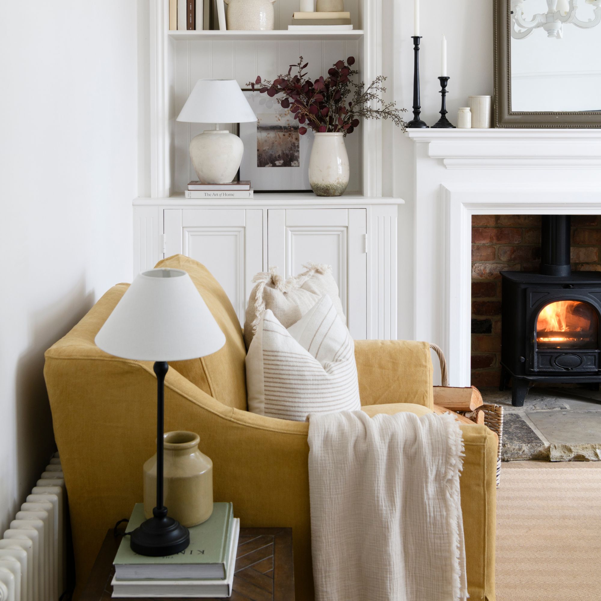 White painted living room with beige carpets and a log burner, with a yellow sofa on the left wall