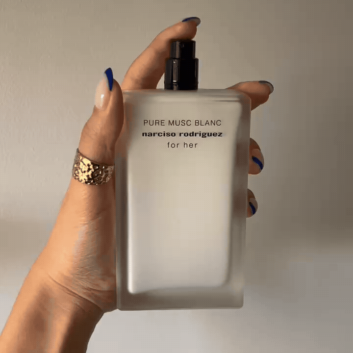 Hand holding white bottle of Narciso Rodriguez For Her Pure Musc Blanc Eau De Parfum Intense and spritzing it