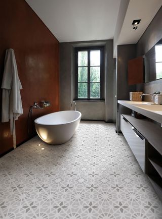 Ceramic gray floor tiles with a matt finish in bathroom with porcelain tub