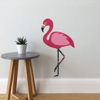 white scheme room with large pink flamingo wall sticker and small side table ith houseplant from chameleon wall art