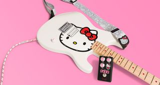 Squier Hello Kitty Stratocaster in new limited-edition white, photographed against a pink background with the new guitar strap and – freshly refinished in black – Hello Kitty op-amp fuzz.
