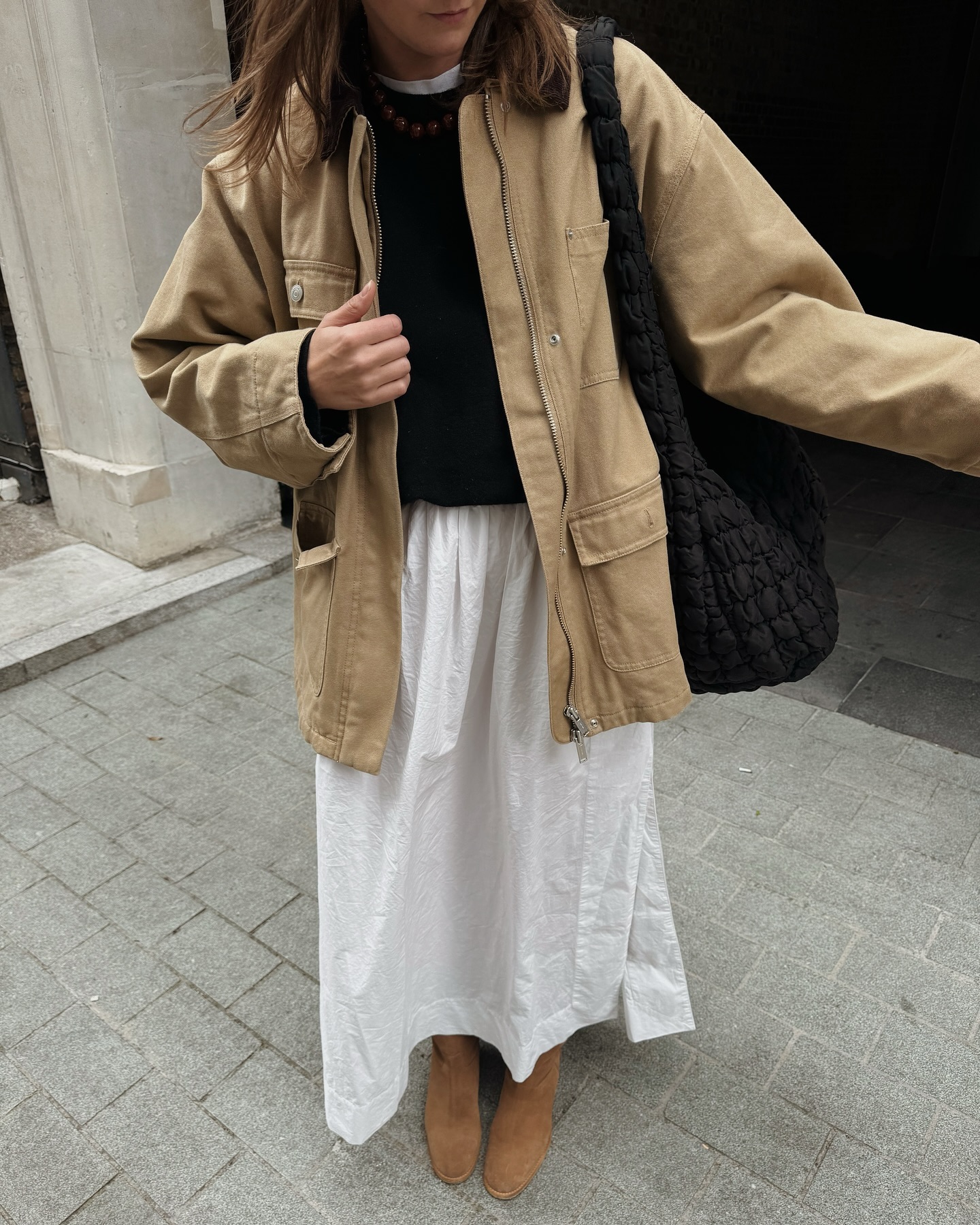 woman wearing a beige canvas jacket with a white cotton skirt