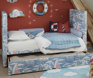 child's bed covered in sail themed fabric with pull out storage drawer