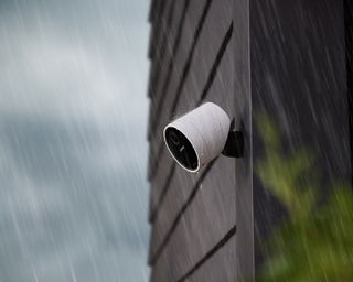 a security camera on the side of a house in low light in the rain