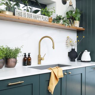 kitchen with blue painted cabinets and gold swan neck tap and granite sink