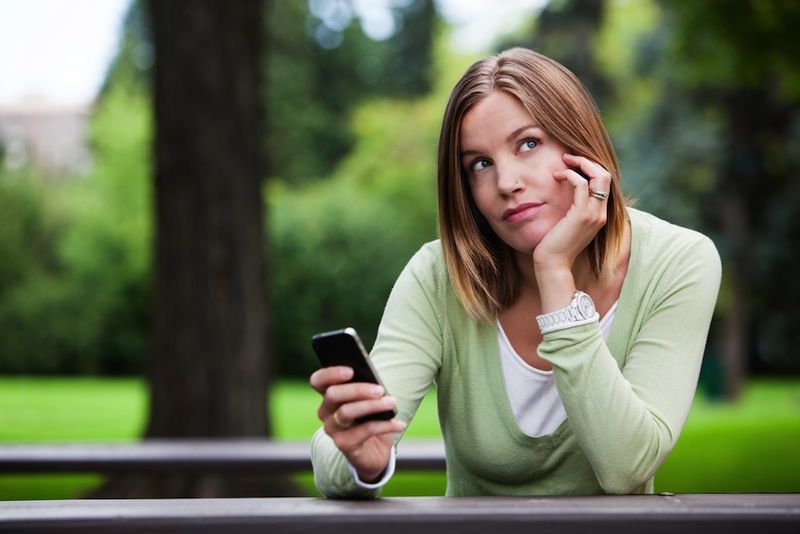 A college woman holds her phone.