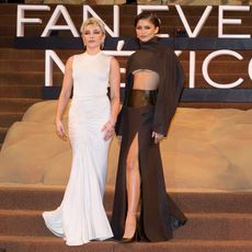 Florence Pugh and Zendaya at Dune photocall. Florence wears a white gown and Zendaya wears a brown two piece. 