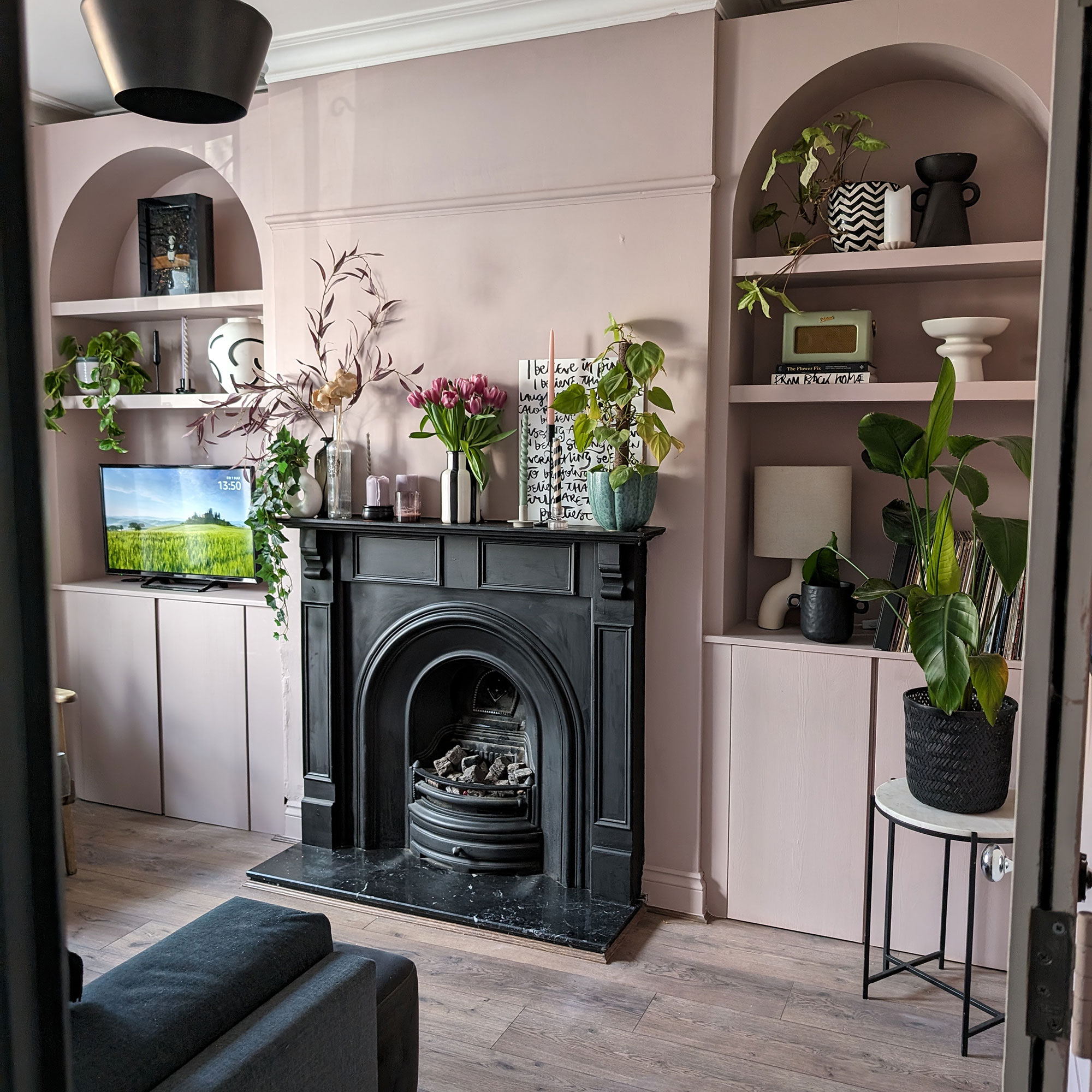 Pale pink living room with arched built-in bookcases on either side of black fireplace