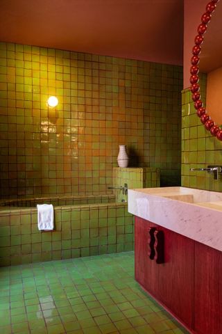 A green and red bathroom with a white sink
