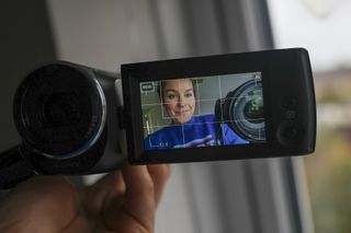 A woman holding a camera up to the Sony HDR-CX405 camcorder with face detection