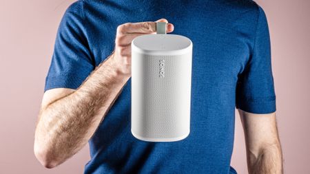 The Sonos Play speaker being held by its carrying hook by man. It's held in front of his body