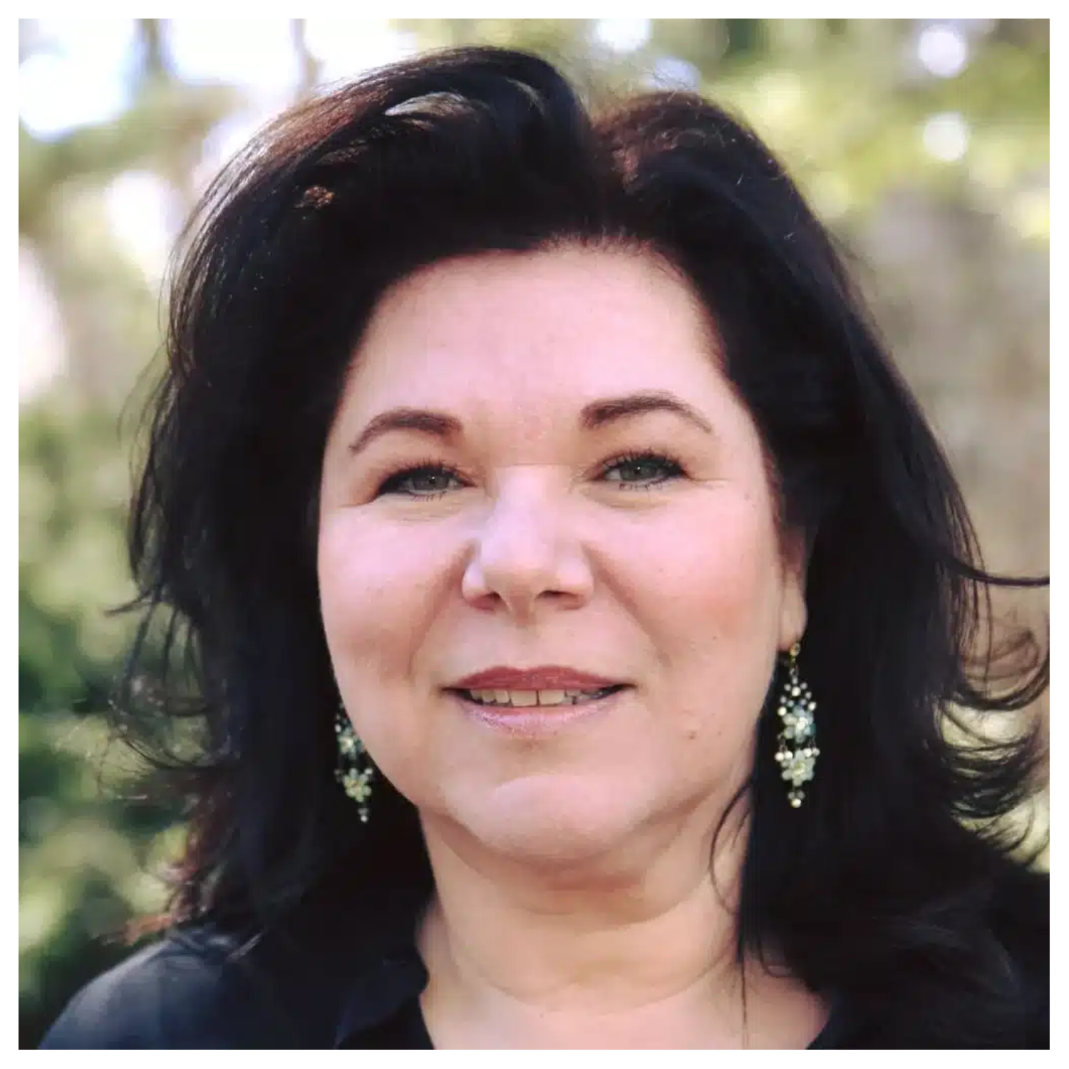 A woman with short black hair, dangling earrings, and a black top